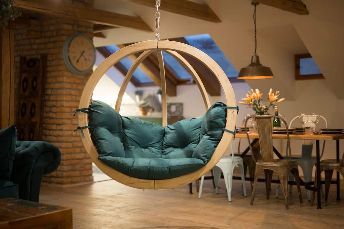 Un interior rústico con una silla colgante, muebles de madera y un comedor.