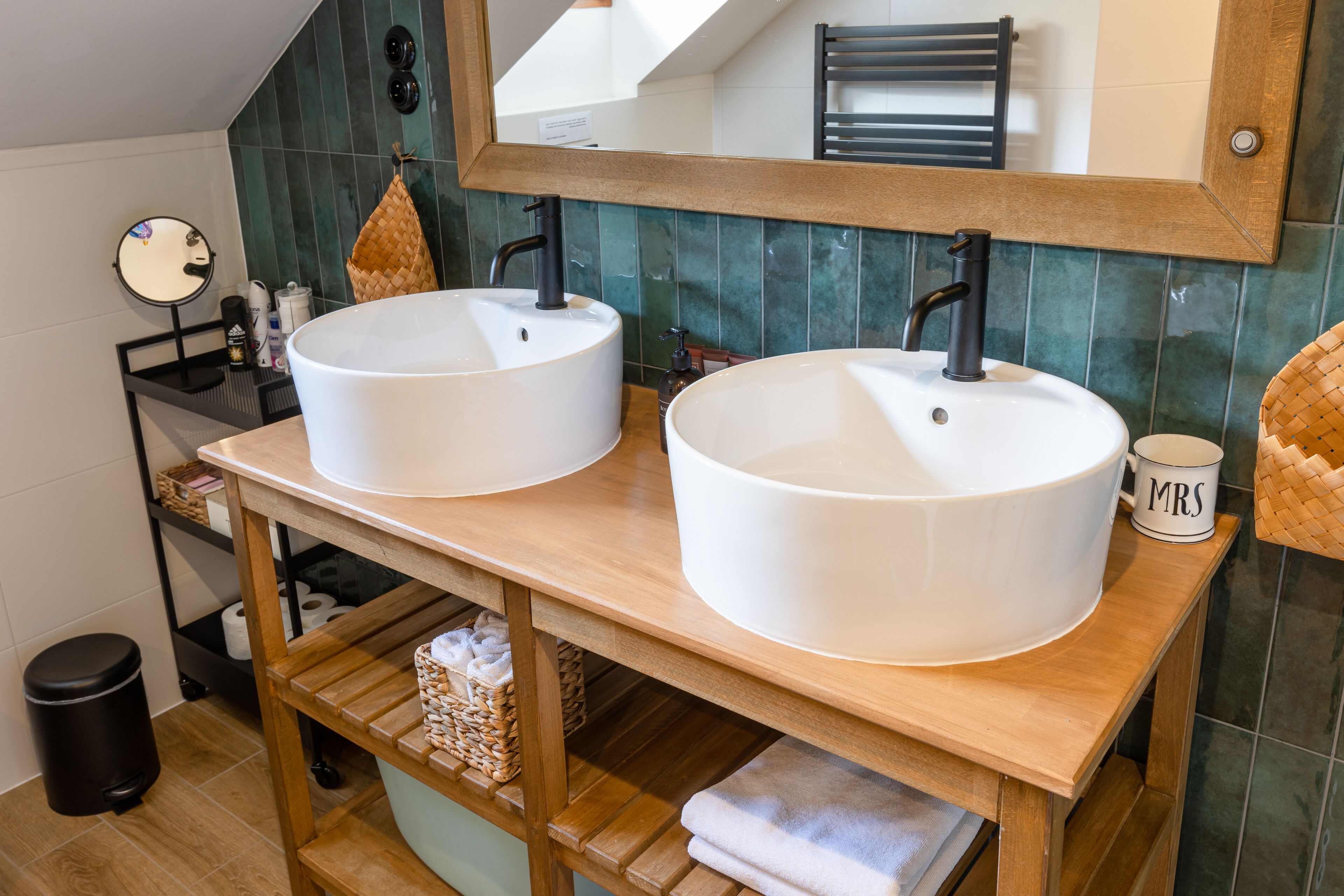 A bathroom with two white sinks, a mirror, and a towel rack.