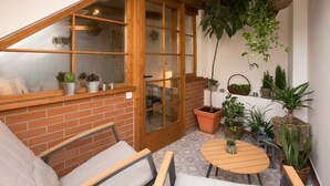 Un patio acogedor con puerta de madera, paredes de ladrillo y diversos maceteros.