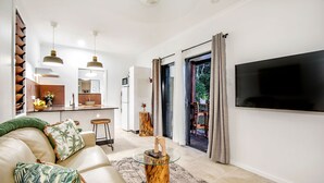A modern living room with a sofa, coffee table, and a flat-screen TV mounted on the wall. - Airlie Beach Eco Cabins - Adults only (Woodwark)