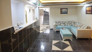 Ein Empfangsbereich mit einer Rezeption, einer Couch und einer Treppe zu einer anderen Etage.
