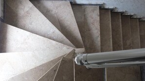 Eine Wendeltreppe mit einem Metallgeländer und einer Reihe beiger Stufen.