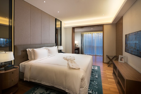 Habitación de hotel con una cama grande, mesitas de noche, un televisor y vistas al exterior.