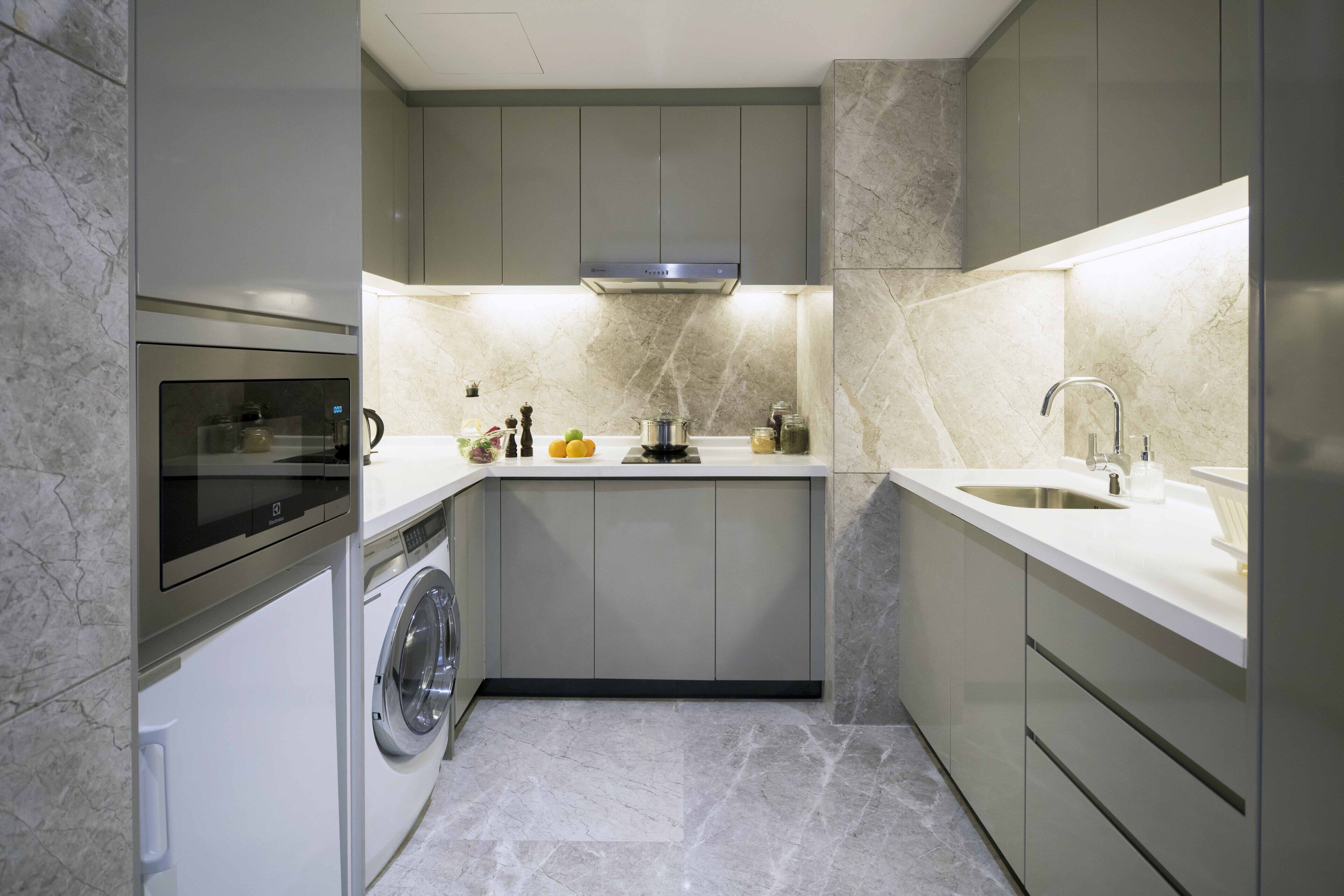 A compact kitchen with a built-in washer and dryer, a stainless steel range hood, and a sink with a modern faucet.
