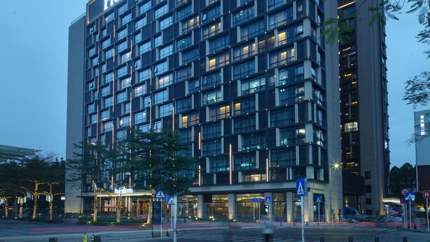 Een meerlaags hotel met een moderne gevel, verlichte reclameborden en een georganiseerd raamwerk.