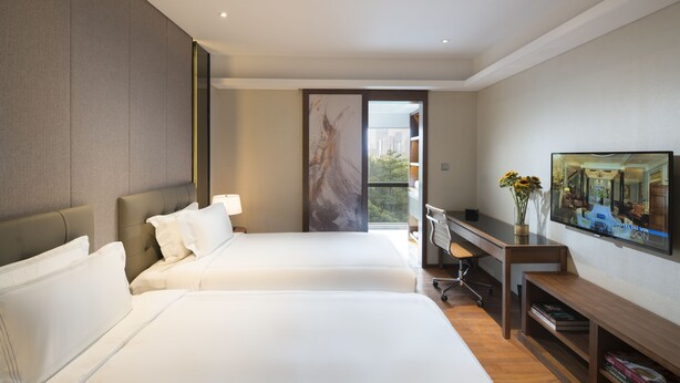 A hotel room with two beds, a desk, a chair, a TV, and a bookshelf. - Fraser Suites Shenzhen (Shenzhen)