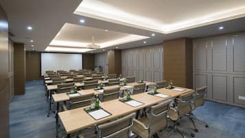 A conference room with multiple tables and chairs, equipped with projectors and screens.