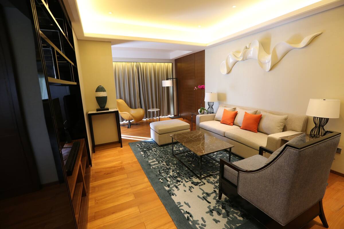 A modern living room with a sofa, armchairs, a coffee table, and a TV.