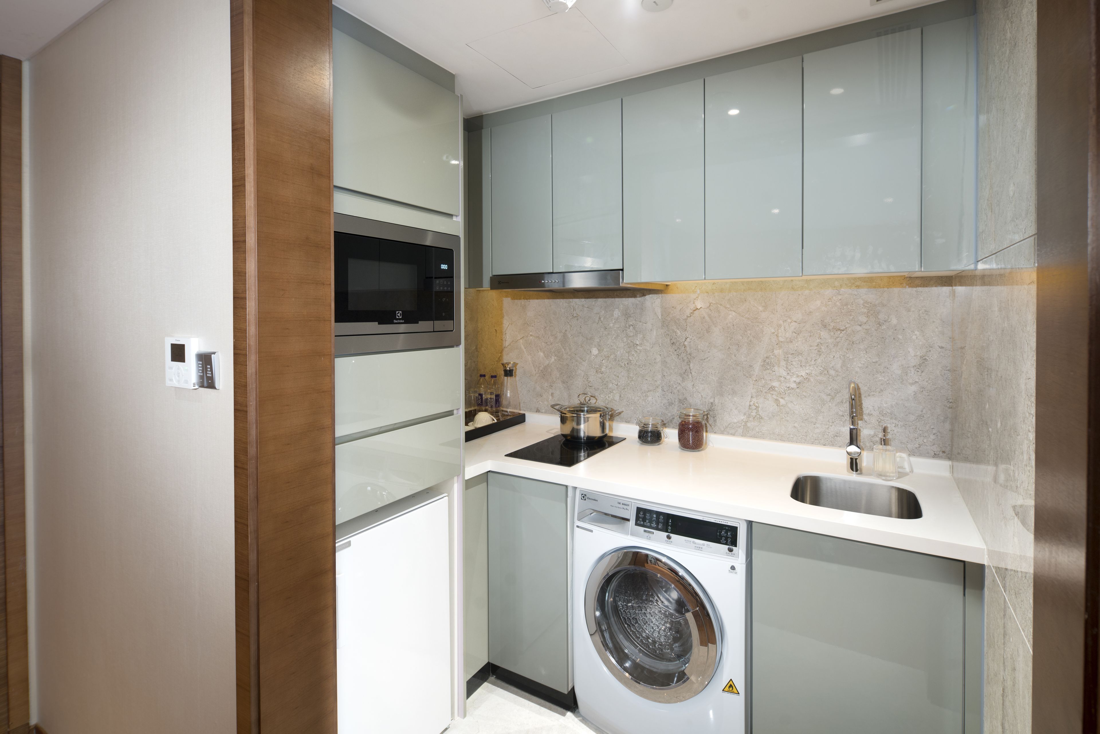A compact kitchen with a built-in microwave, stainless steel sink, and a washing machine.