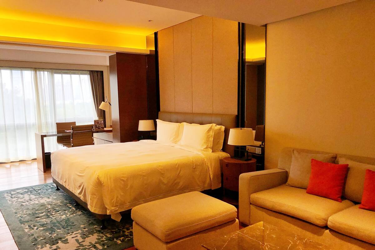 A hotel room with a large bed, a sofa, a coffee table, and a desk with a chair.