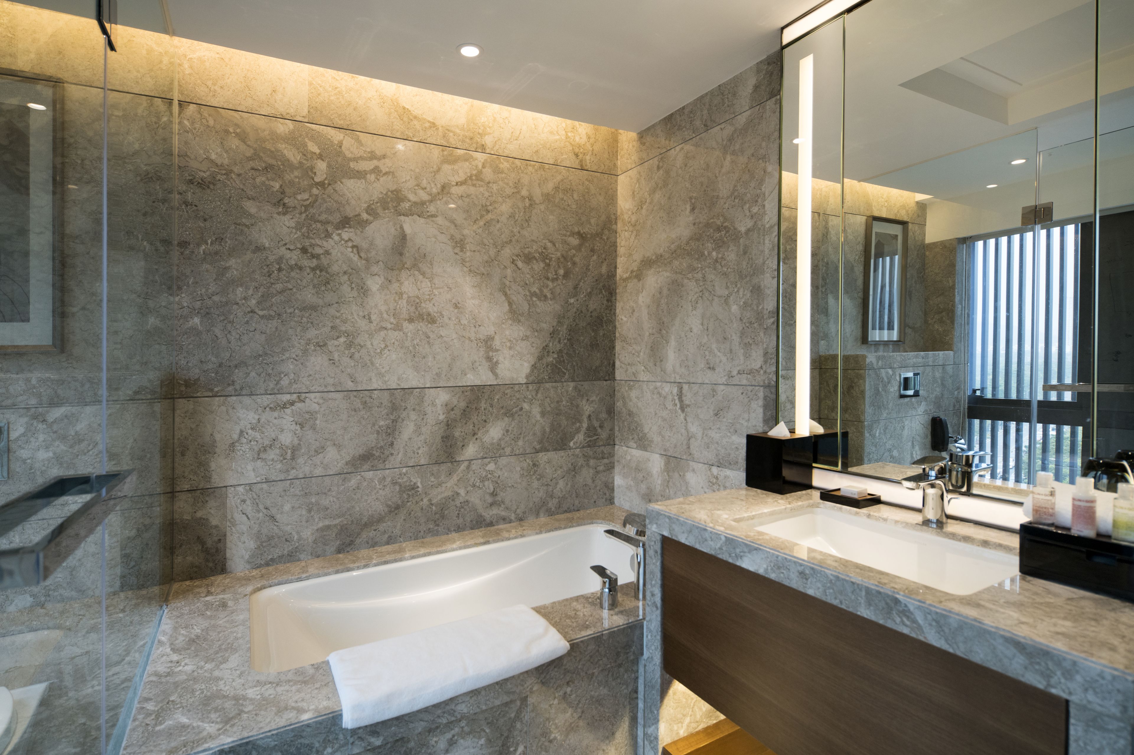 A modern bathroom with a large bathtub, a double sink vanity, and a large mirror.
