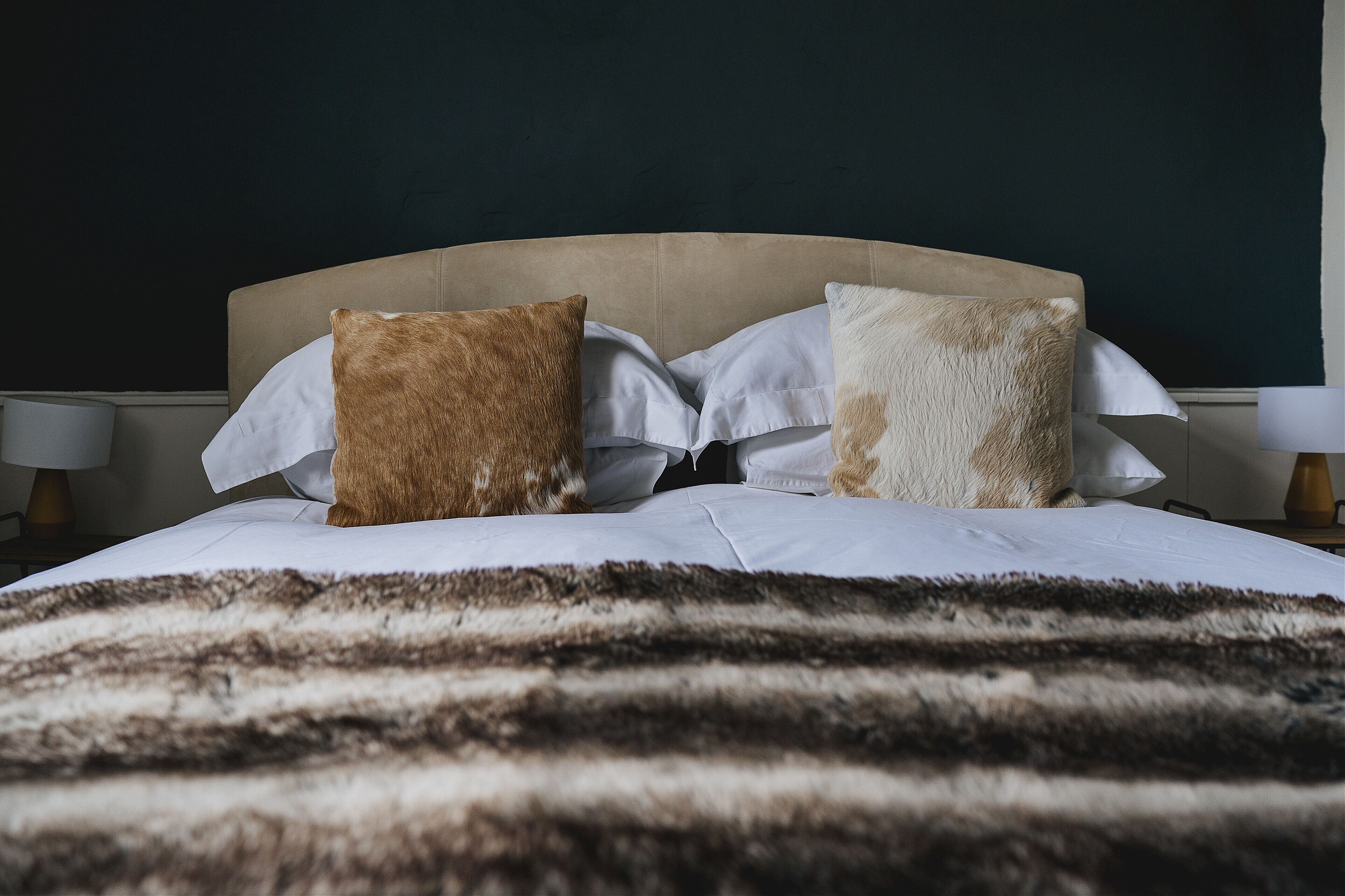 Una cama con una colcha a rayas, dos almohadas y un cabecero.