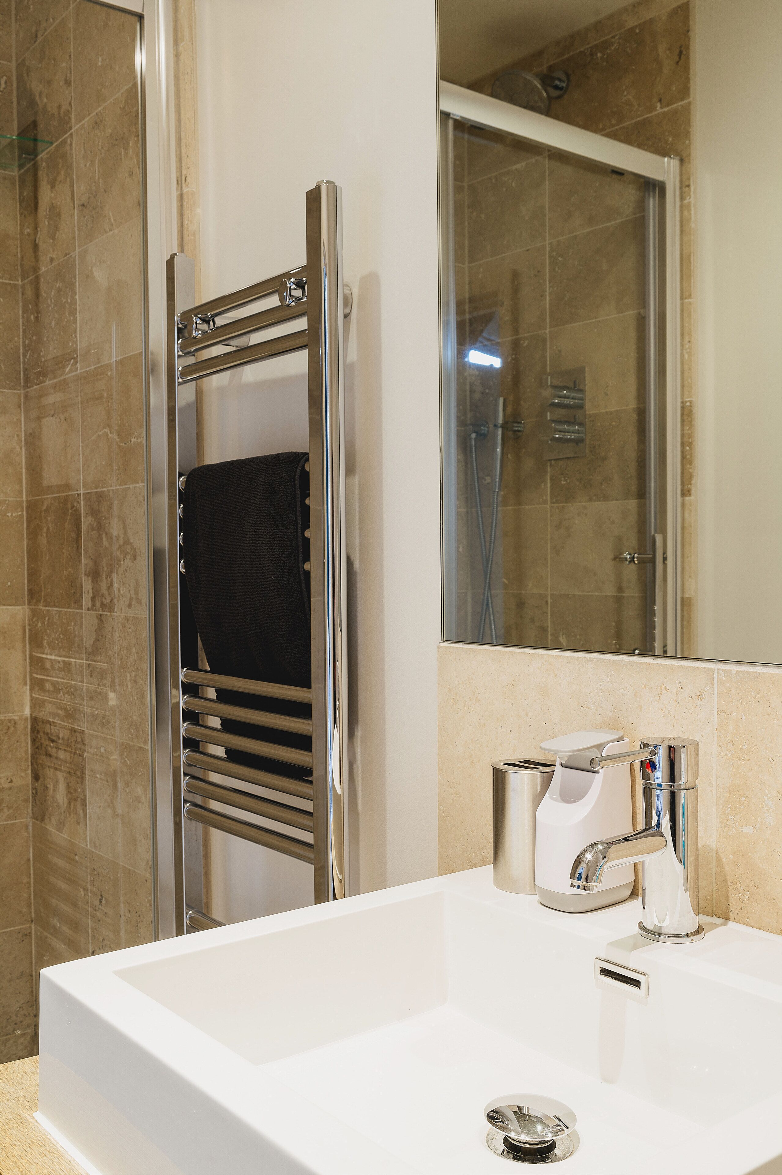 A modern bathroom with a white sink, chrome fixtures, and a glass shower enclosure.