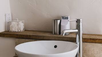 A bathroom with a white sink, a round mirror, and a chrome faucet.