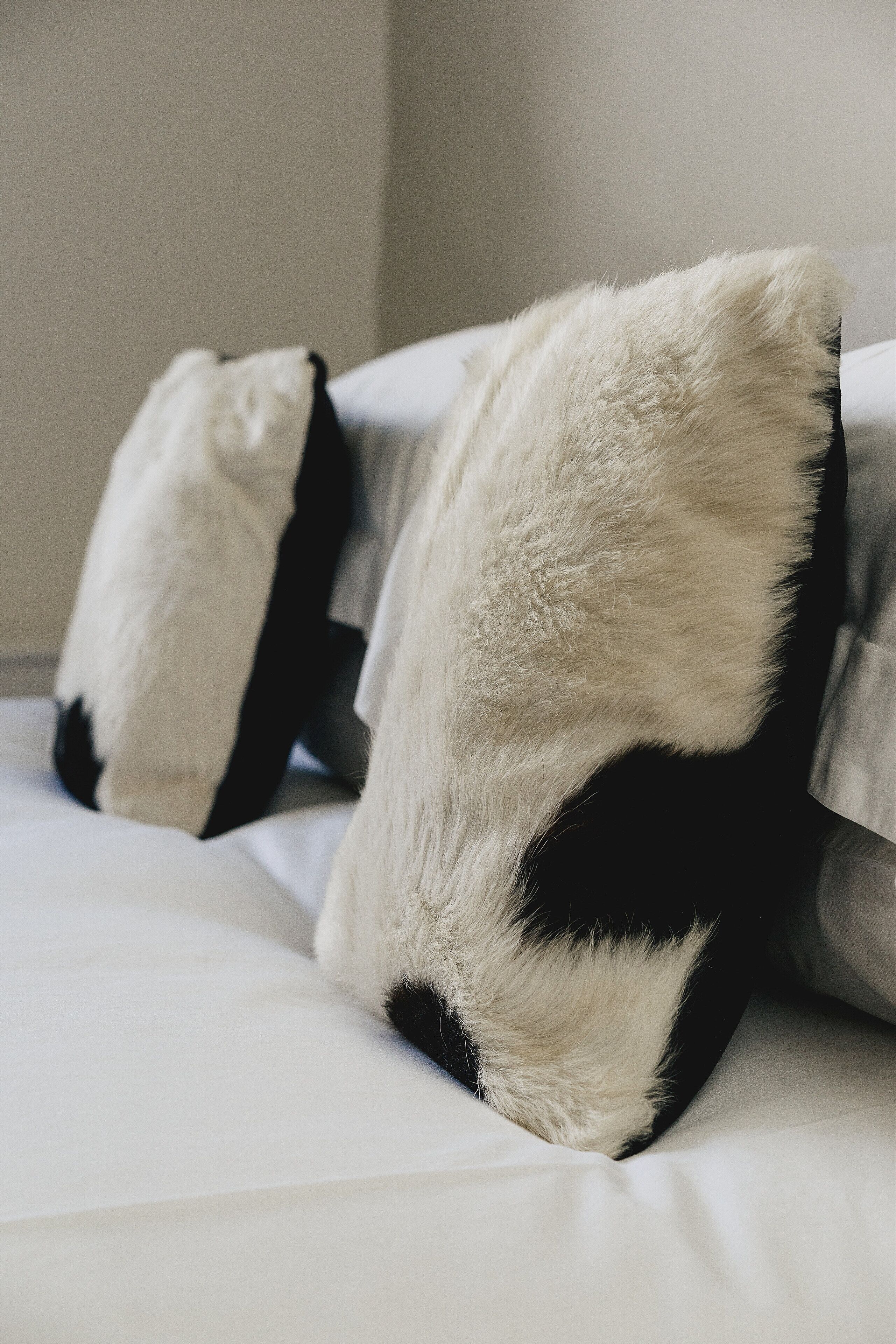 Una cama con ropa de cama blanca y dos almohadas estampadas en blanco y negro.