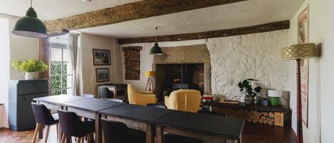 A dining area with a long table, chairs, and a fireplace.