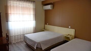 Habitación de hotel con dos camas, una mesita de noche con teléfono y un equipo de aire acondicionado en la pared.