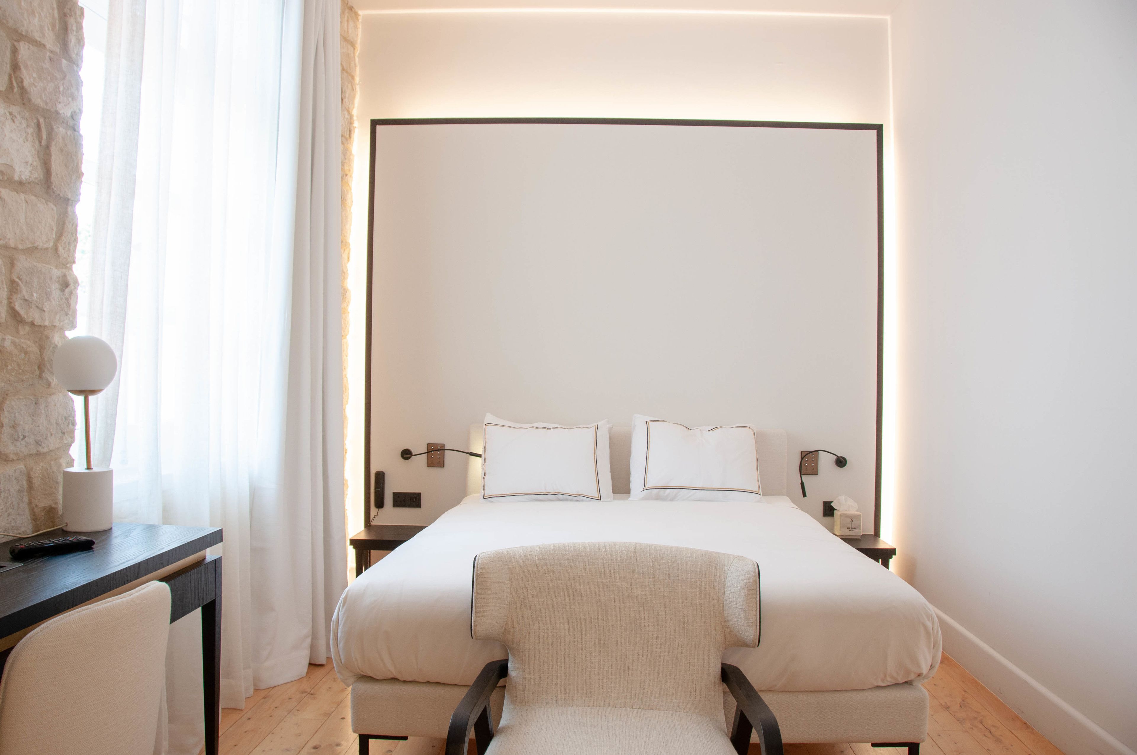 Una habitación de hotel moderna con una cama grande, un escritorio y una silla.