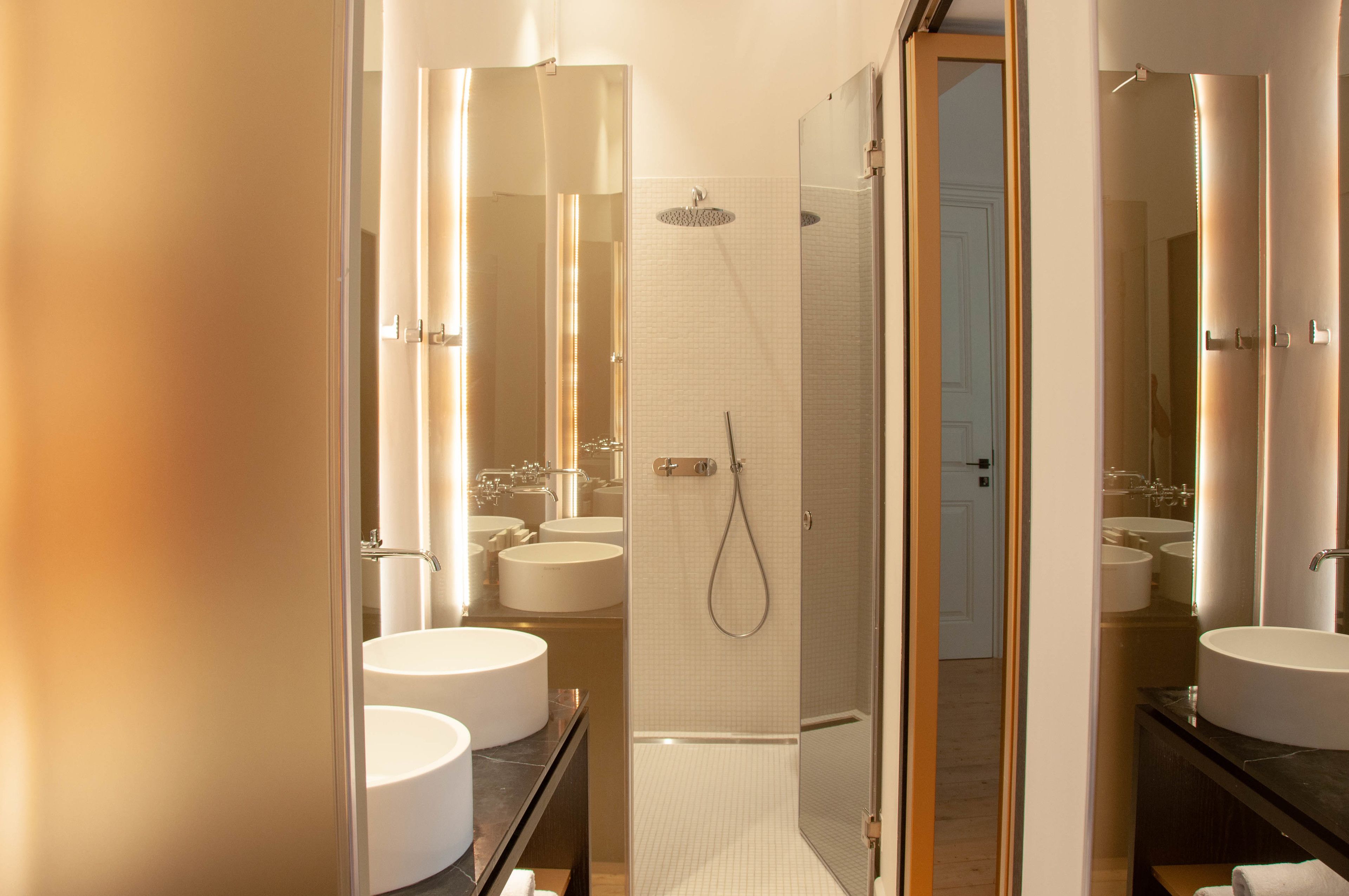 A modern bathroom with two sinks, a shower, and a glass-enclosed shower area.