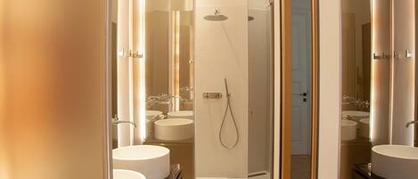 A modern bathroom with two sinks, a shower, and a glass-enclosed shower area.