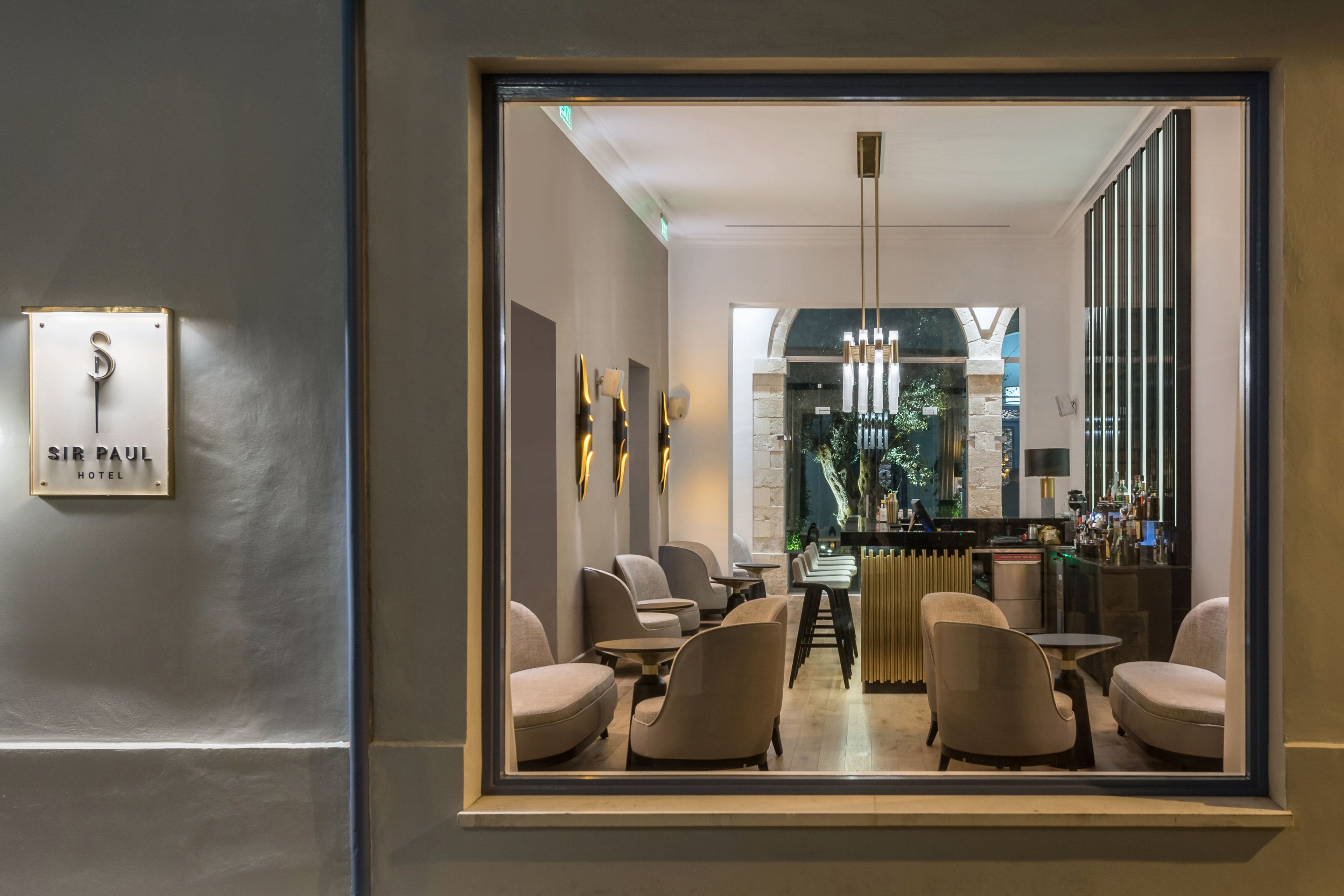 A modern hotel lobby with a bar area, seating, and a sign reading "SIR PAUL HOTEL".