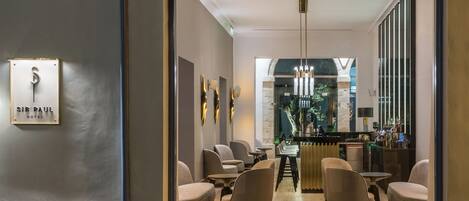 A modern hotel lobby with a bar area, seating, and a sign reading "SIR PAUL HOTEL".