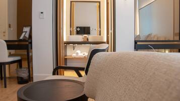Relax in a serene space with a large bed, round side table, and cozy seating area.