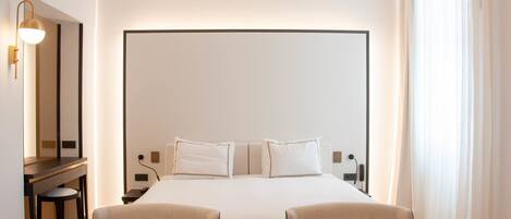 A hotel room with a large bed, two bedside tables, a desk, and two chairs.