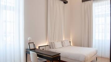 A bedroom with a bed, a desk, and a chair.