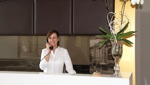 Un comptoir d’accueil agrémenté d’un arrangement floral blanc et, en arrière-plan, un tableau représentant un bâtiment.