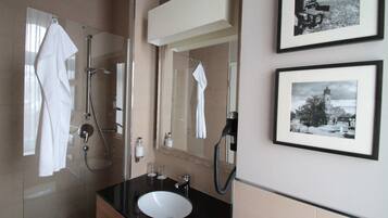 Een badkamer met een wastafel, spiegel, handdoekhouder en douche.