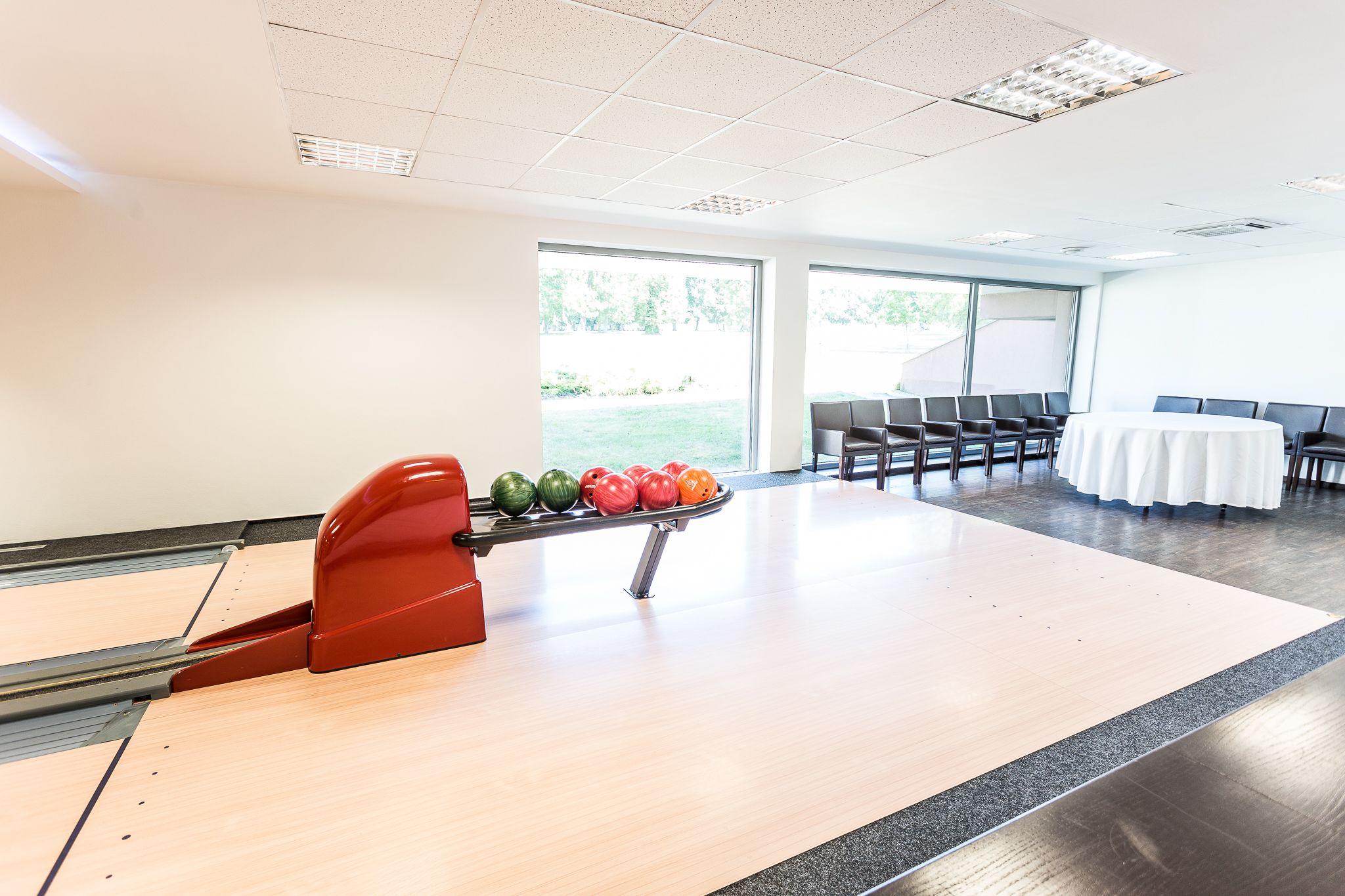 A bowling alley with a bowling lane, a pinsetter, and a row of chairs.