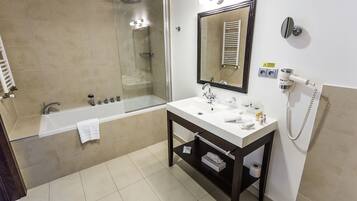 Un baño moderno con bañera, lavamanos con espejo y secador de pelo en la pared.