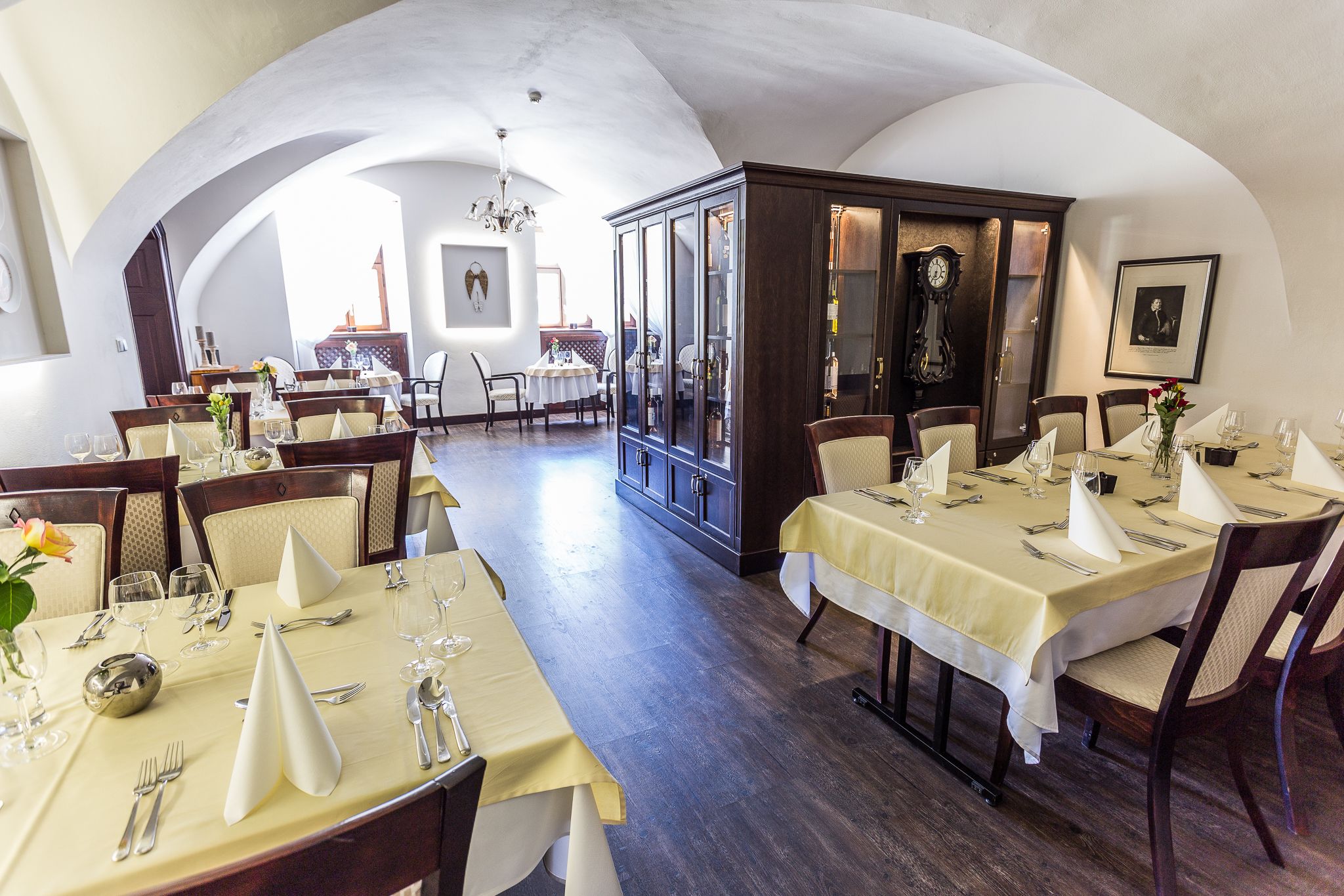 Un restaurante con varias mesas dispuestas para comer, que presenta un interior clásico con mobiliario de madera y un candelabro.