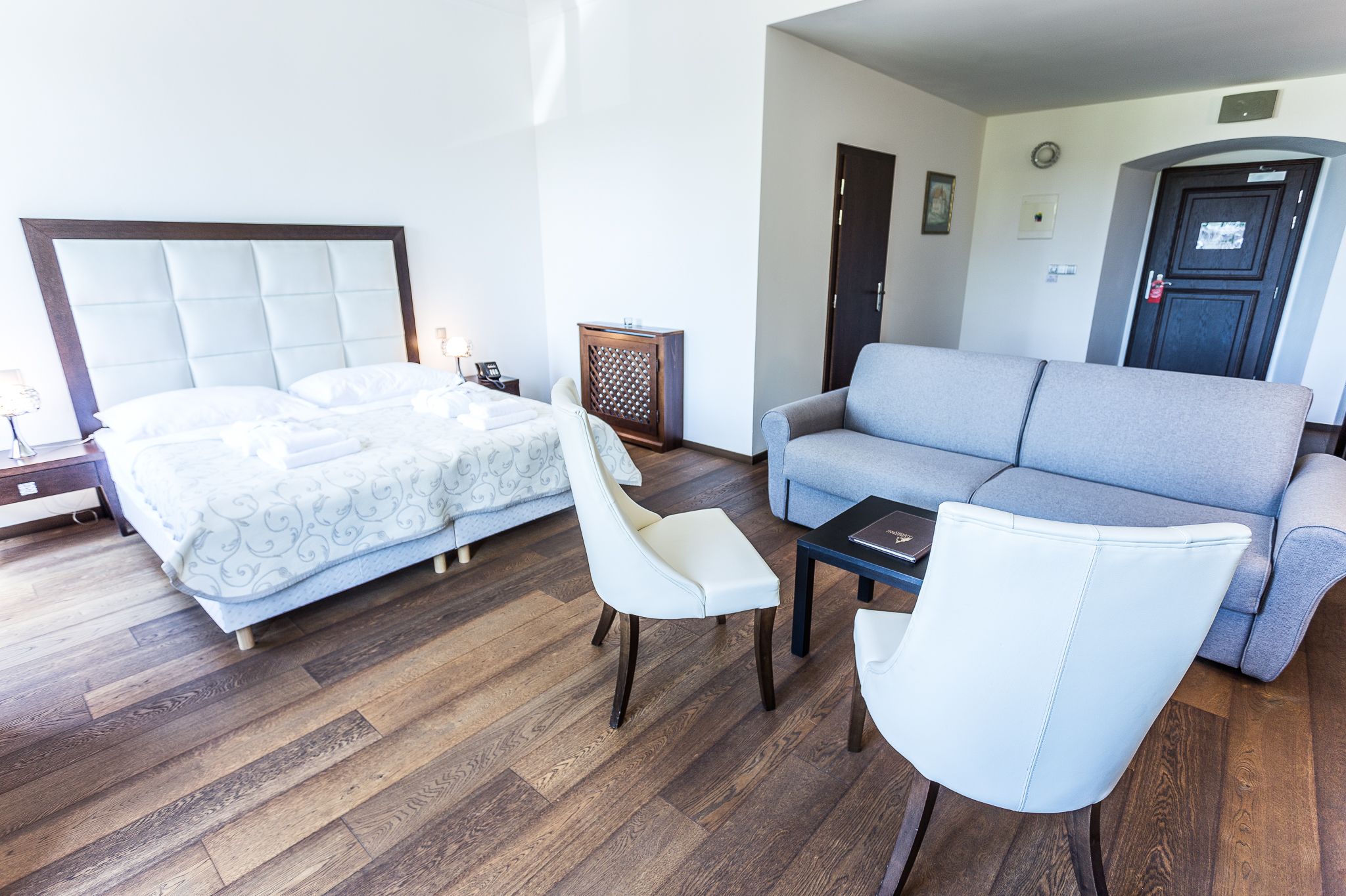 A bedroom with a bed, a sofa, a chair, and a small table.