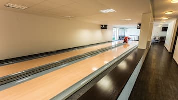 En bowlinghall med en bana av trä, ett mörkt golv och ett tak med infälld belysning.