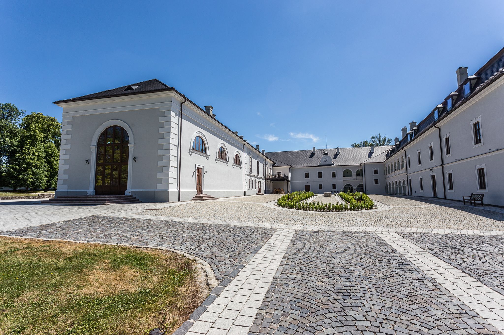 A courtyard with a white building featuring arched windows and a central garden.