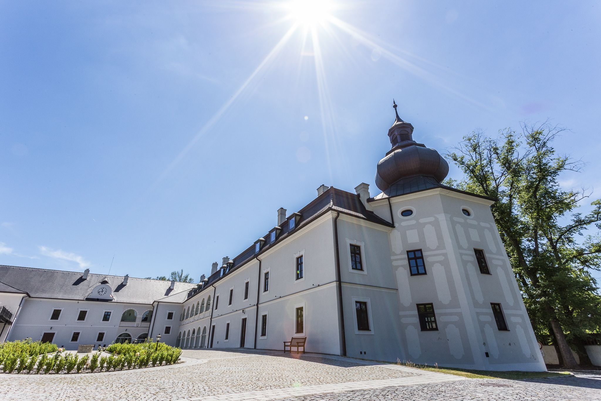 A historic building with a prominent tower and a courtyard.