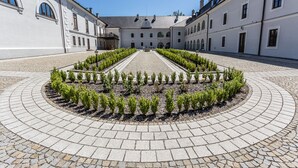 A courtyard with a symmetrical garden, paved walkways, and classical architecture. - Chateau Appony (Oponice)