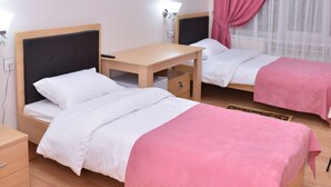A hotel room with two beds, a desk, and a window with pink curtains. - Planet Inn Hotel Baku (Baku)