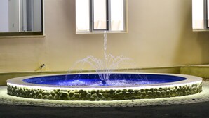A circular fountain with water jets, surrounded by a stone border, and a window above it. - Planet Inn Hotel Baku (Baku)