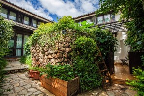 A courtyard with a stone wall, wooden planter boxes, and a wooden deck.