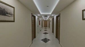 A long, narrow hallway with a ceiling light, framed pictures on the walls, and a tiled floor. - Apameia Hotel (Mudanya)
