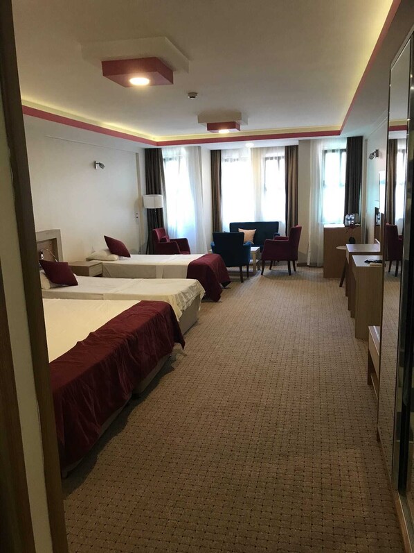 Habitación de hotel con dos camas, un escritorio, una silla y un sofá.