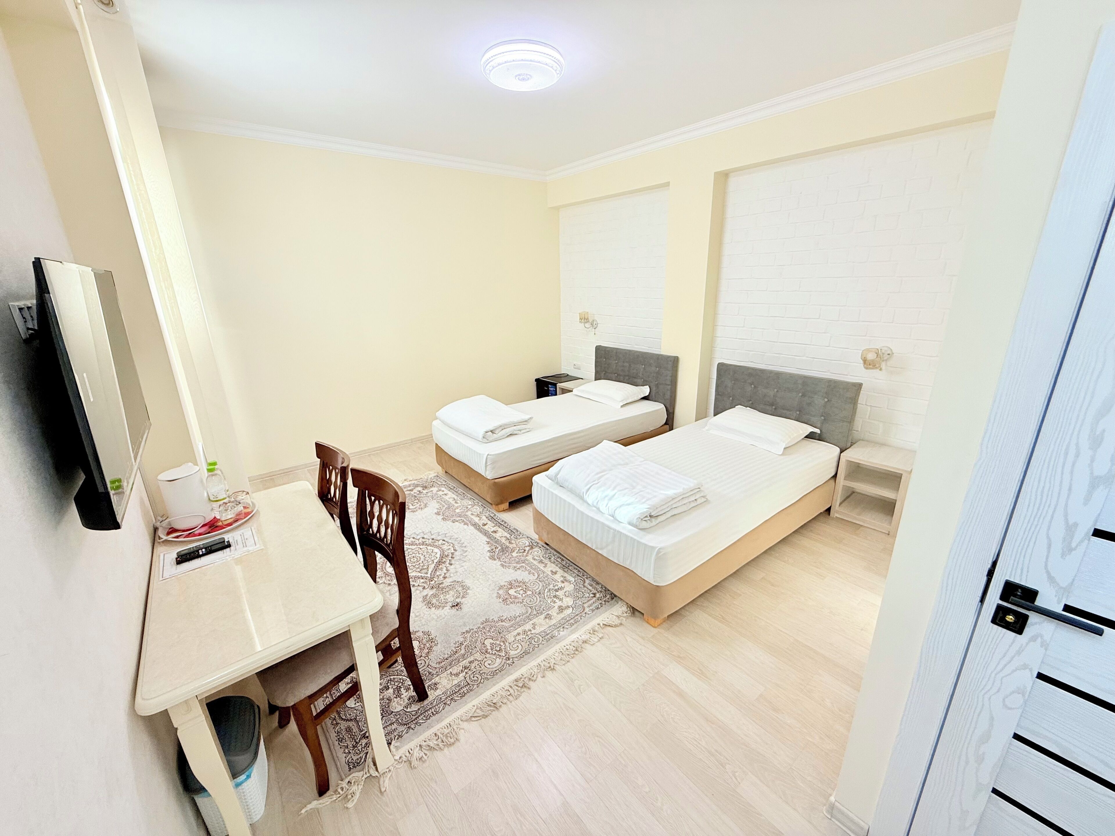 Hotellihuone, jossa on kaksi sänkyä, työpöytä ja tuoli.