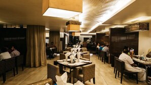 A restaurant with tables set for dining, a patterned ceiling, and a modern interior design. - The Royale Senate Hebbal (Bengaluru)
