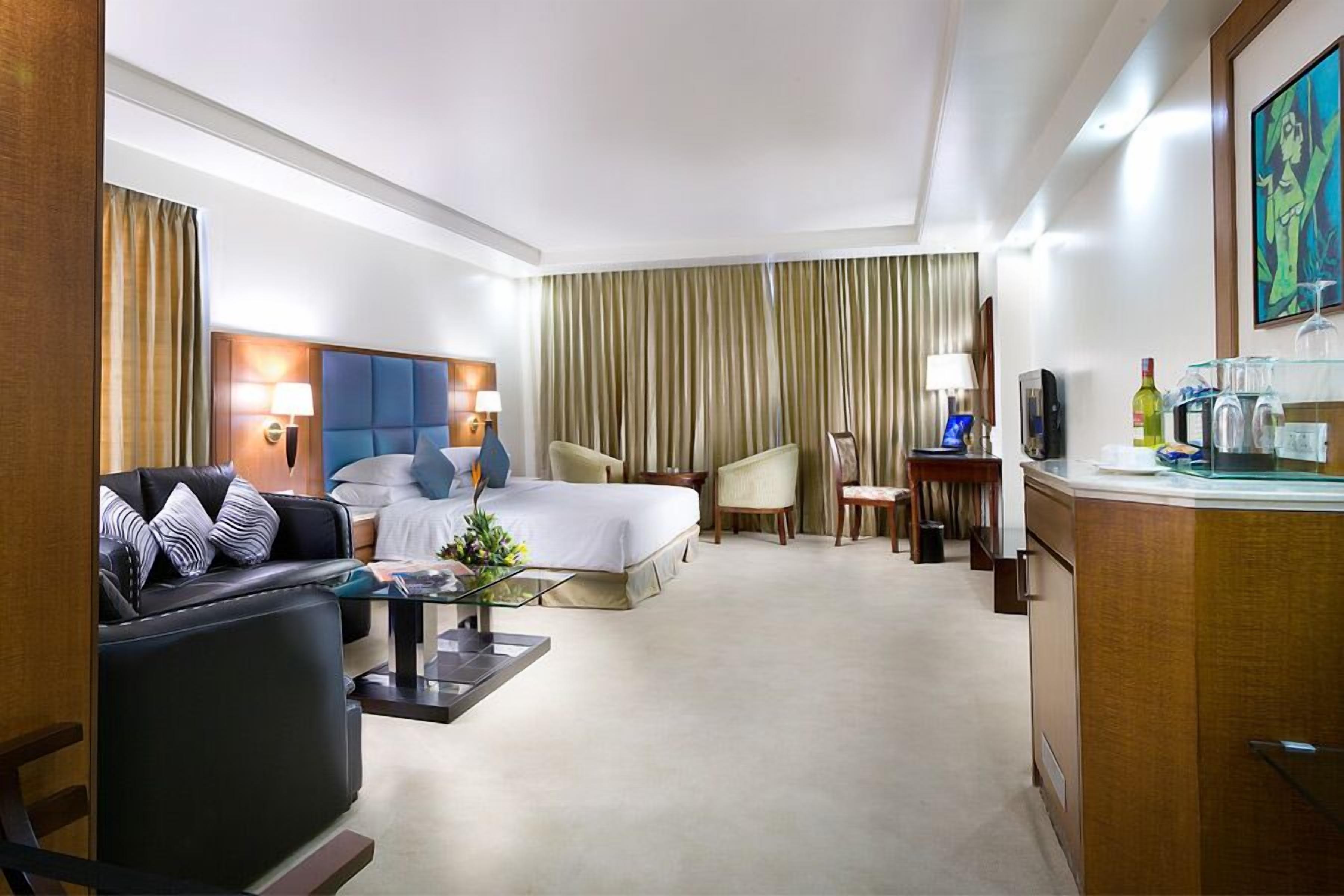 A hotel room with a bed, a sofa, a desk, and a television.