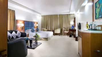 A hotel room with a bed, a sofa, a desk, and a television.