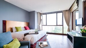 A hotel room with a bed, a sofa, a TV, and a window with curtains. - Nice Residence Hotel Huahin (Hua Hin)