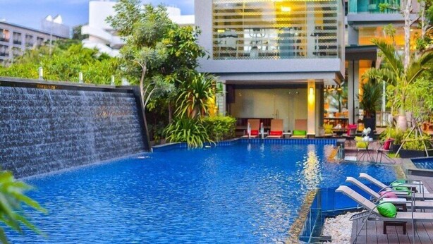 A modern hotel with a swimming pool, outdoor seating, and lush greenery. - Nice Residence Hotel Huahin (Hua Hin)